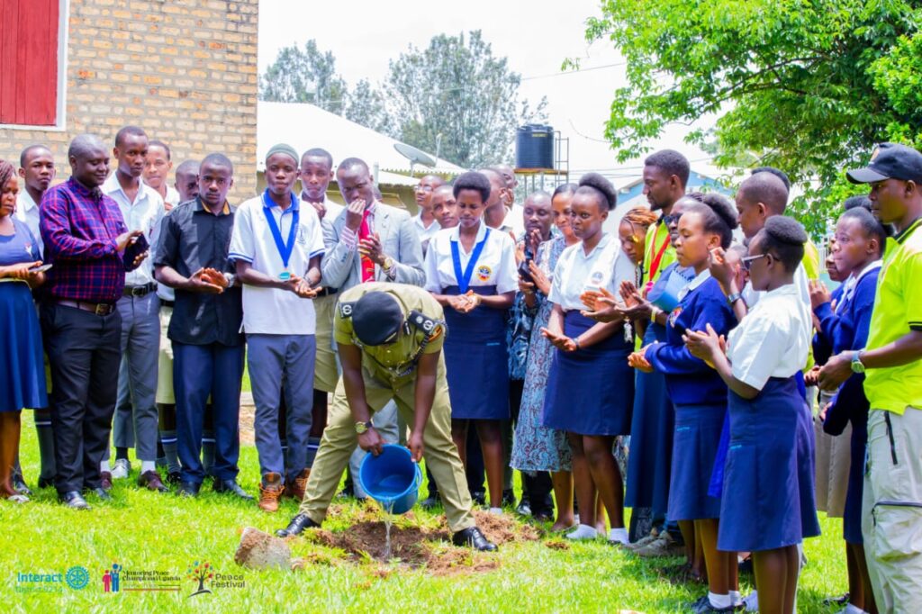 A guest of honour watering a newly planted tree as students applaud