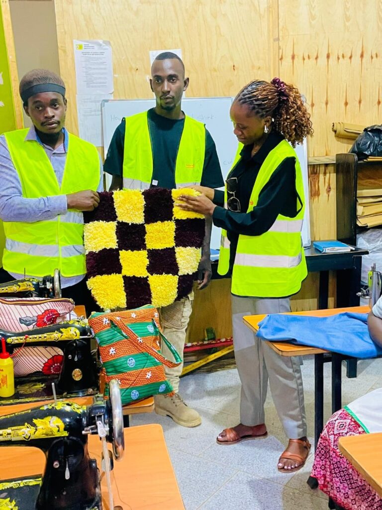 She Means Business trainees presenting a finished handmade rug in the tailoring and sustainable fashion workshop