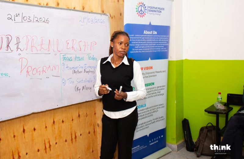 A facilitator opening an Entrepreneurship 4 Peace session at the whiteboard beside the PPG banner