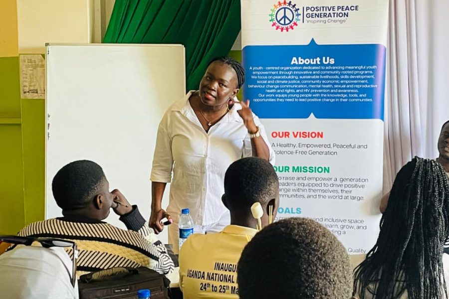 A facilitator addressing Entrepreneurship 4 Peace participants beside the PPG banner